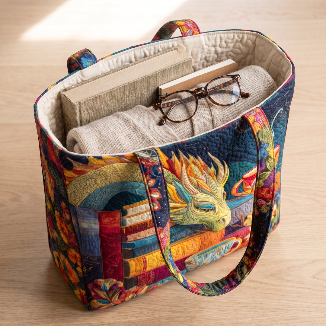 Bolso Artesanal — Dragón Lector con Libros y Tazas: con un libro de tapa dura, un suéter doblado y lentes de lectura