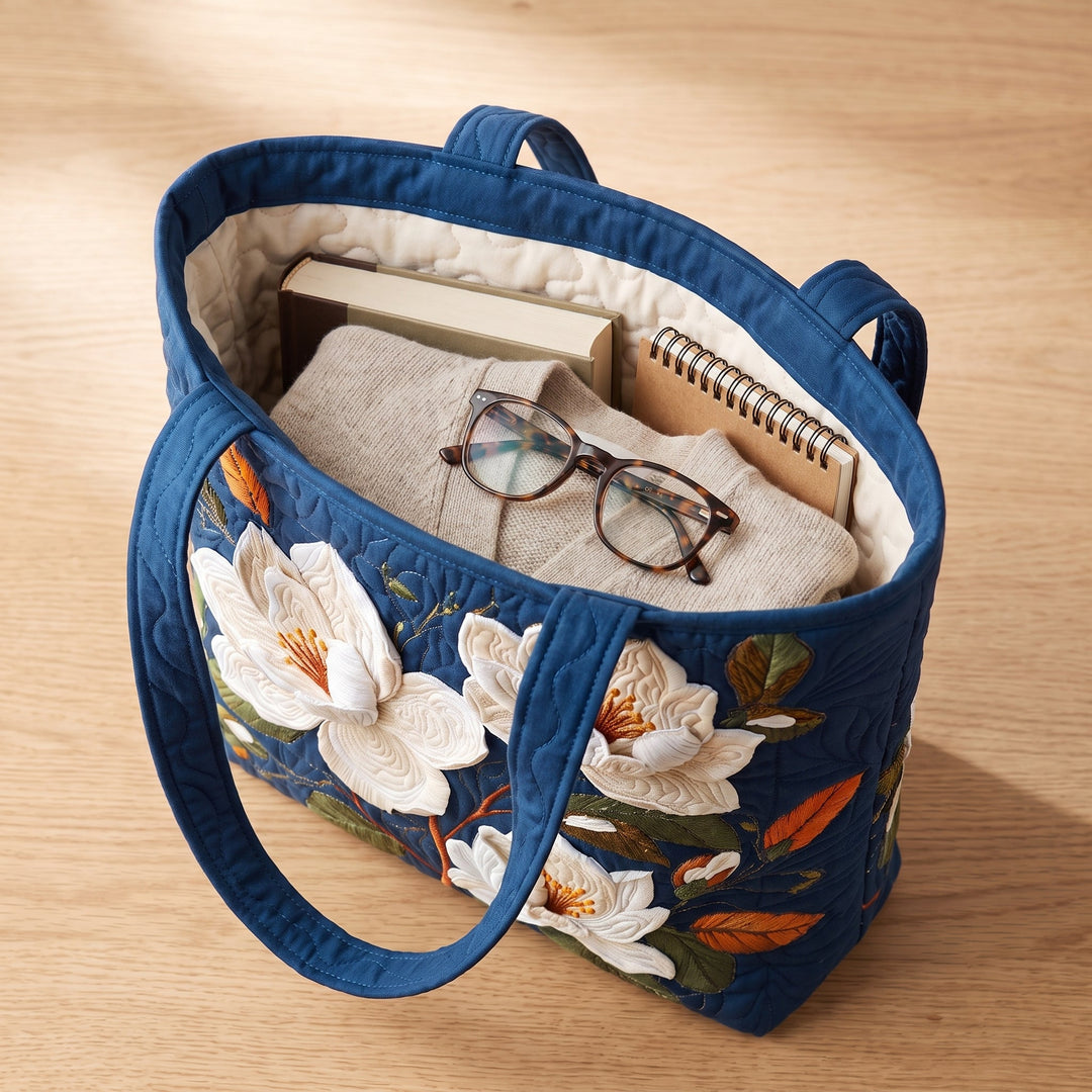 Bolso Artesanal Acolchado — Magnolia Delicada: con un libro de tapa dura, un suéter doblado y lentes de lectura